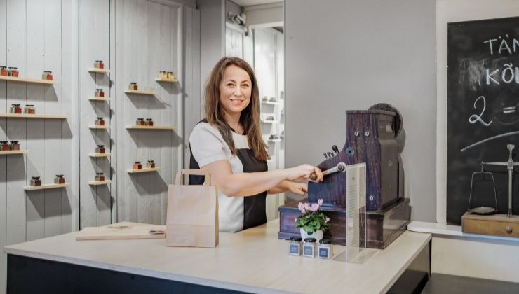 naiskauppias seisoo myyntitiskin takana valmiina auttamaan asiakkaita