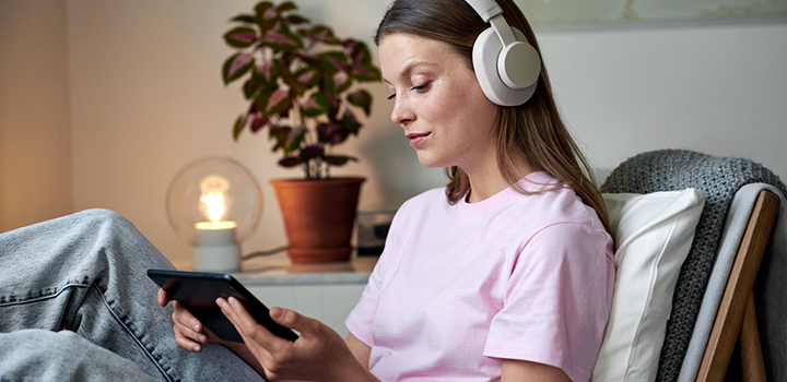 Nainen kuuntelee musiikkia ja hoitaa sähkösopimus asioita