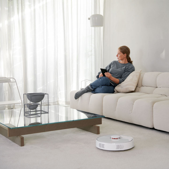 Nainen istuu sohvalla tablettitietokoneen kanssa